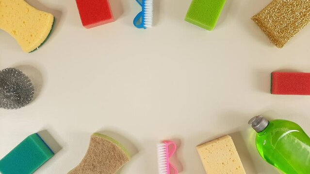 Cleaning household goods appear on top and bottom of pastel beige background. Stop motion with empty space for text, advertising, design
