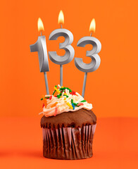 Birthday cupcake with number 133 candle - Orange color background