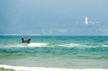 Nutshell boat on the waves and Lady Buddha in Da Nang in Vietnam