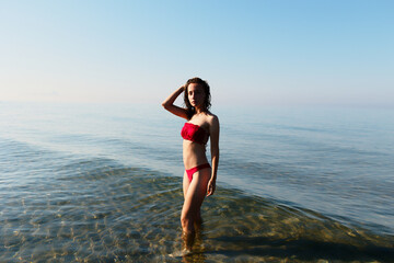 Young bikini model at the beach in red swimsuit. Summer holiday at the seaside where you can swim...