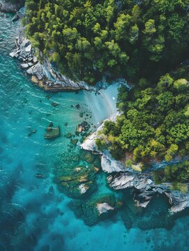 Aerial shot captures a pristine beach with turquoise waters, a lush island to the right, and striking rocks below, blending nature's palette.