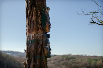 Two mystical masks on a tree  - obrazy, fototapety, plakaty
