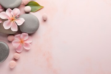 Top view of white flowers with smooth pebbles on pink background. Copy space, spa concept