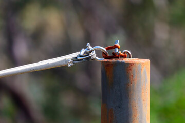 Photograph of a rusty shackle attached to a stainless steel connector on the top of a rusty painted...