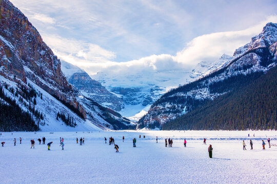 Visitors skating on frozen Lake Louise in Winter against the backdrop of the stunning Victoria Glacier