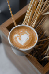 Cappuccino on a wooden stand with dried flowers.