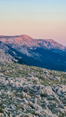 Obraz premium Panoramic view majestic mountain ranges around coastal town Baska, Krk Otok, Primorje-Gorski Kotar, Croatia, Europe. Hiking on deserted barren terrain. Alpine landscape. Vibrant coloured sky. Tranquil