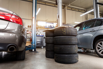 Car wheel repair with two auto lift back view. Seasonal winter tyre change at workshop. Vehicle...