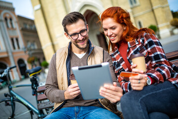 Trendy young couple in town using tablet and credit card.