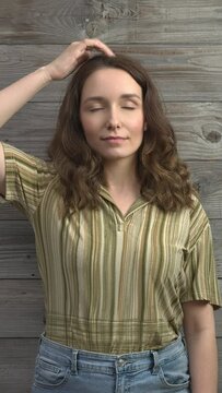 Person practicing EFT. Female tapping top of head (TH) meridian point. Vertical video.