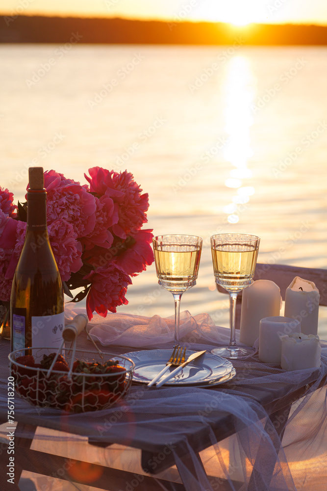 Wall mural romantic sunset dinner on the beach. table honeymoon set for two with luxurious food, glasses of cha