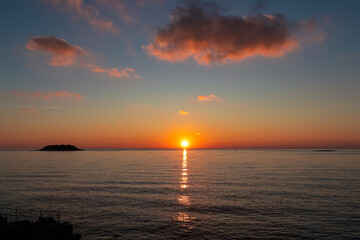 Naklejka premium Watching dramatic sunset at coastal village Funtana, Istria, Croatia, EU. Silhouette of remote tropical island. Calm sea surface reflects vibrant colors of sky. Vacation at Adriatic Mediterranean Sea