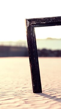 Empty wooden picture frame on the beach sand