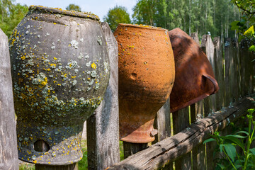 Clay brown jugs on a rural fence - 756719495