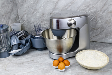 Modern food processor, eggs and plate with flour on a kitchen table