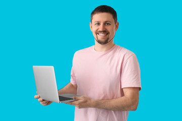 Handsome man with laptop on blue background