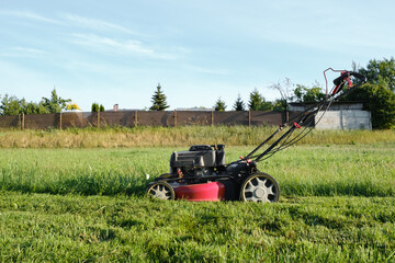 Lawn mower on green grass background in the garden. Machine for cutting lawns. Cutting of meadow...