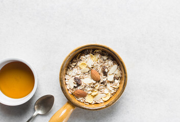 Top view of oat muesli in a brown terracotta ramekin with handle, overhead view of muesli with oats...