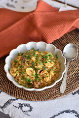 plate of rice with squid decorated with green leaves. it is on a brown placemat with a spoon on the side and an orange tea towel. all very homemade.