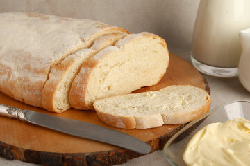 Wooden board with bread and bowl of butter on white background