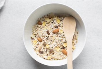 Top view of oat muesli in a white ceramic bowl, overhead view of muesli with oats almonds raisins...