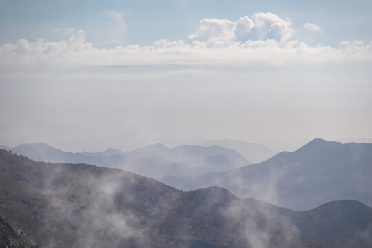 Panoramic view of mystical fog covered mountain ranges of Biokovo nature park near Makarska, Dalmatia, Croatia. Scenic hiking trail in karst landscape in Dinaric Alps in summer. Wanderlust atmosphere