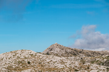Fototapeta na wymiar Panoramic view of alpine cottage near mountain peak Vosac in Biokovo nature park, Makarska, Dalmatia, Croatia. Scenic hiking trail in remote karst landscape. Dinaric Alps in summer. Barren wilderness
