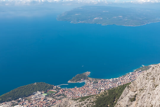 Panoramic aerial view of coastal town Makarska seen from skywalk in Biokovo nature park, Dalmatia, Croatia. Majestic karst coastline of Adriatic Mediterranean sea in summer. Tranquil serene atmosphere