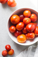 Overhead view of red tomatoes in a white ceramic bowl, Top view of round orange and red tomatoes in a white bowl