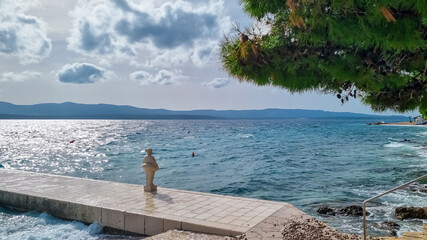 White stone sculpture of girl with lifebelt on a pier in coastal town of Bol island Brac, Dalmatia, Croatia. Travel destination in summer. Coastline of Adriatic Mediterranean Sea. Tranquil atmosphere