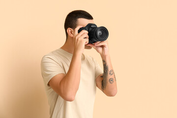 Male photographer with modern camera on beige background © Pixel-Shot