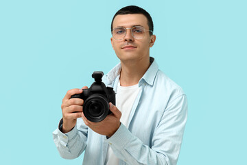 Male photographer with modern camera on blue background