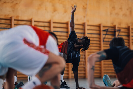 African american basketball player is stretching on court on training.