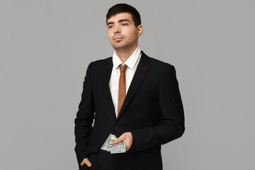 Young businessman with bribe on light background