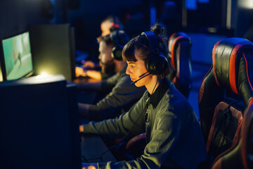 Fototapeta premium Young woman gamer playing online video games and streaming during tournament