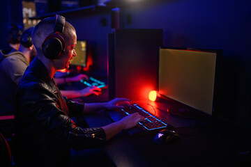 Bald female esport gamer playing video games in an internet cafe