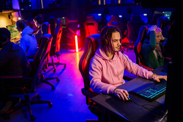 Esport male gamer with dreadlocks playing online video games in a gaming club