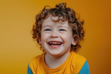 A cheerful little boy with curly hair smiling at the camera. Suitable for various uses