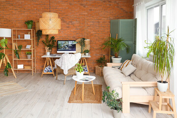 Interior of office with workplace, green plants and sofa