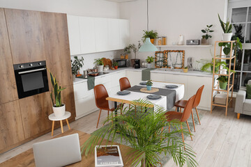 Interior of modern kitchen with green plants, dining table and counters