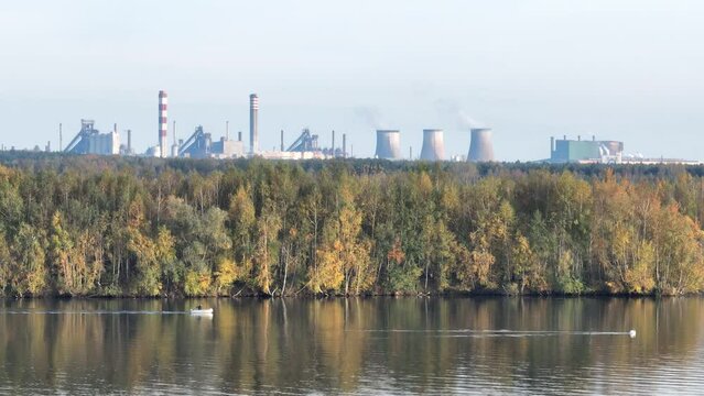 Industrial steel factory, iron works. Metallurgical plant. steelworks. Heavy industry in Europe. Air pollution from chimneys. Ironworks on a background of blue lake. Drone fly above lake to iron works