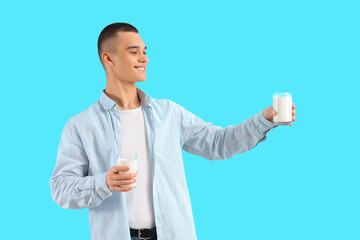 Teenage boy with glasses of milk on blue background