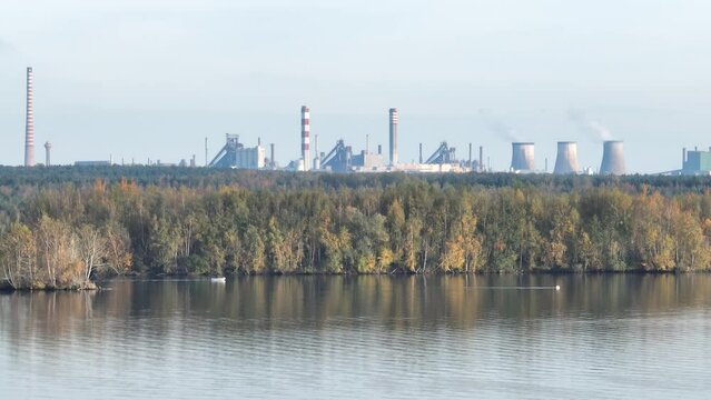 Industrial steel factory, iron works. Metallurgical plant. steelworks. Heavy industry in Europe. Air pollution from chimneys. Ironworks on a background of blue lake. Drone fly above lake to iron works