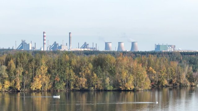 Industrial steel factory, iron works. Metallurgical plant. steelworks. Heavy industry in Europe. Air pollution from chimneys. Ironworks on a background of blue lake. Drone fly above lake to iron works