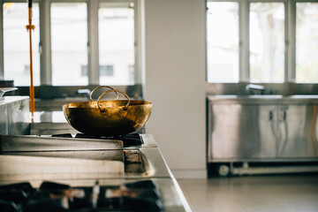 Shiny metal bowl occupies stove in a professional kitchen of a modern restaurant. Clean arrangement...