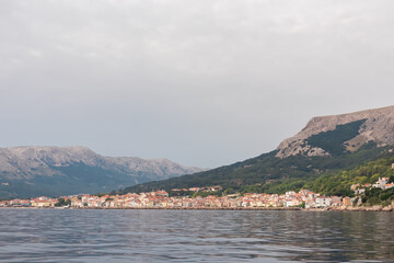 Fototapeta premium Scenic view of idyllic coastal town Baska, Krk Island, Primorje-Gorski Kotar, Croatia, Europe. Majestic coastline with high mountains and steep cliffs. Mediterranean Adriatic architecture of old town