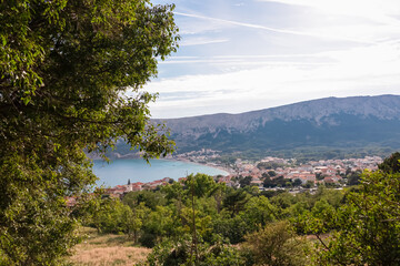 Fototapeta premium Aerial view of idyllic coastal town Baska, Krk Island, Primorje-Gorski Kotar, Croatia, Europe. Majestic coastline with high mountains and steep cliffs. Mediterranean Adriatic architecture of old town