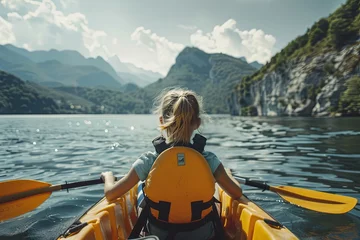 Gordijnen A child girl floats a kayak on a mountain river in a life jacket © Vitalii Shkurko