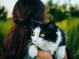 A woman is tenderly holding a black and white cat in her arms.