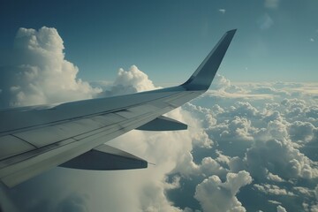 An airplane wing cuts through the sky, soaring above a blanket of fluffy white clouds.